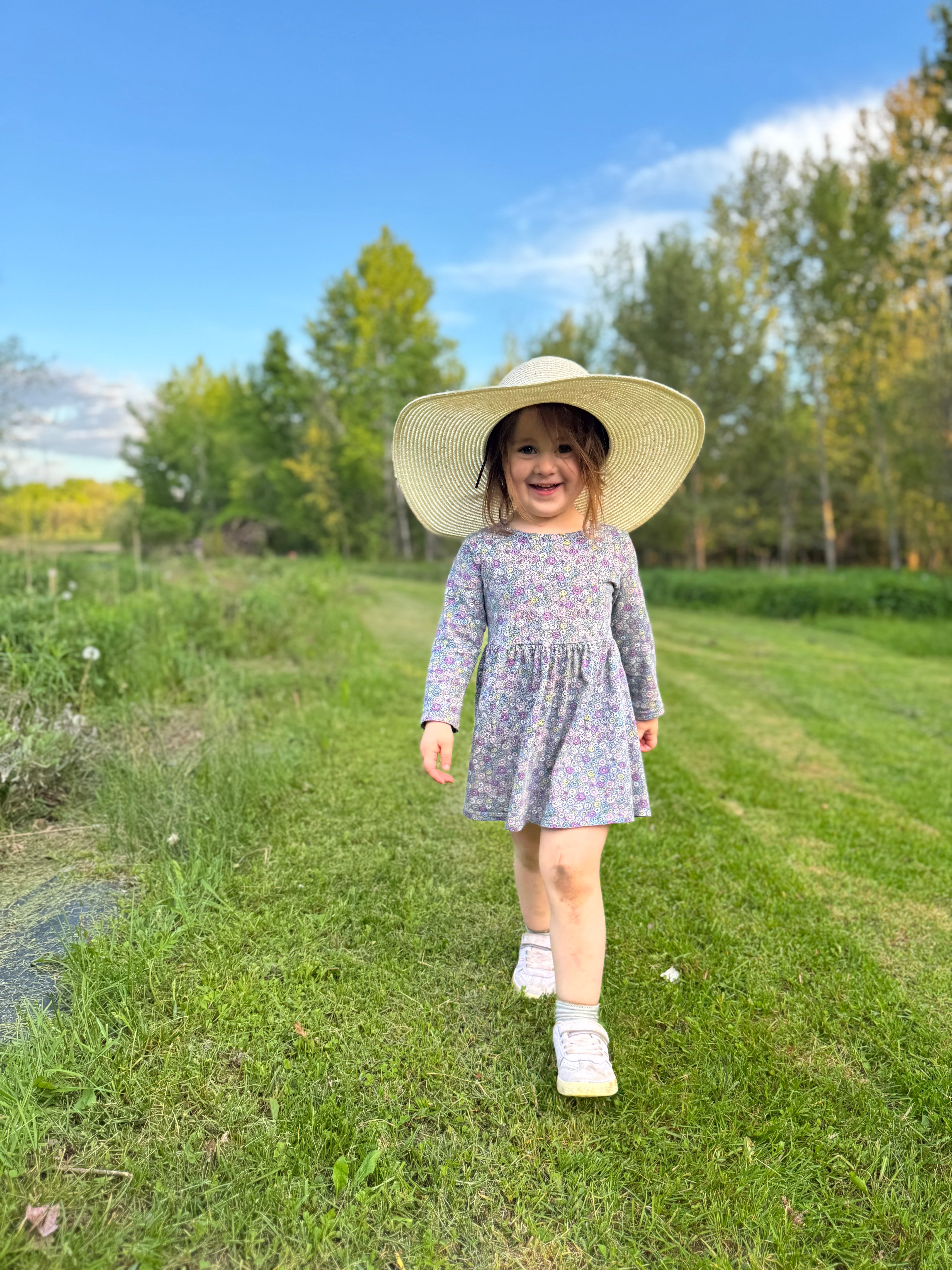 Eulalie qui porte un grand chapeau de paille dans les jardins de la Val'heureuse
