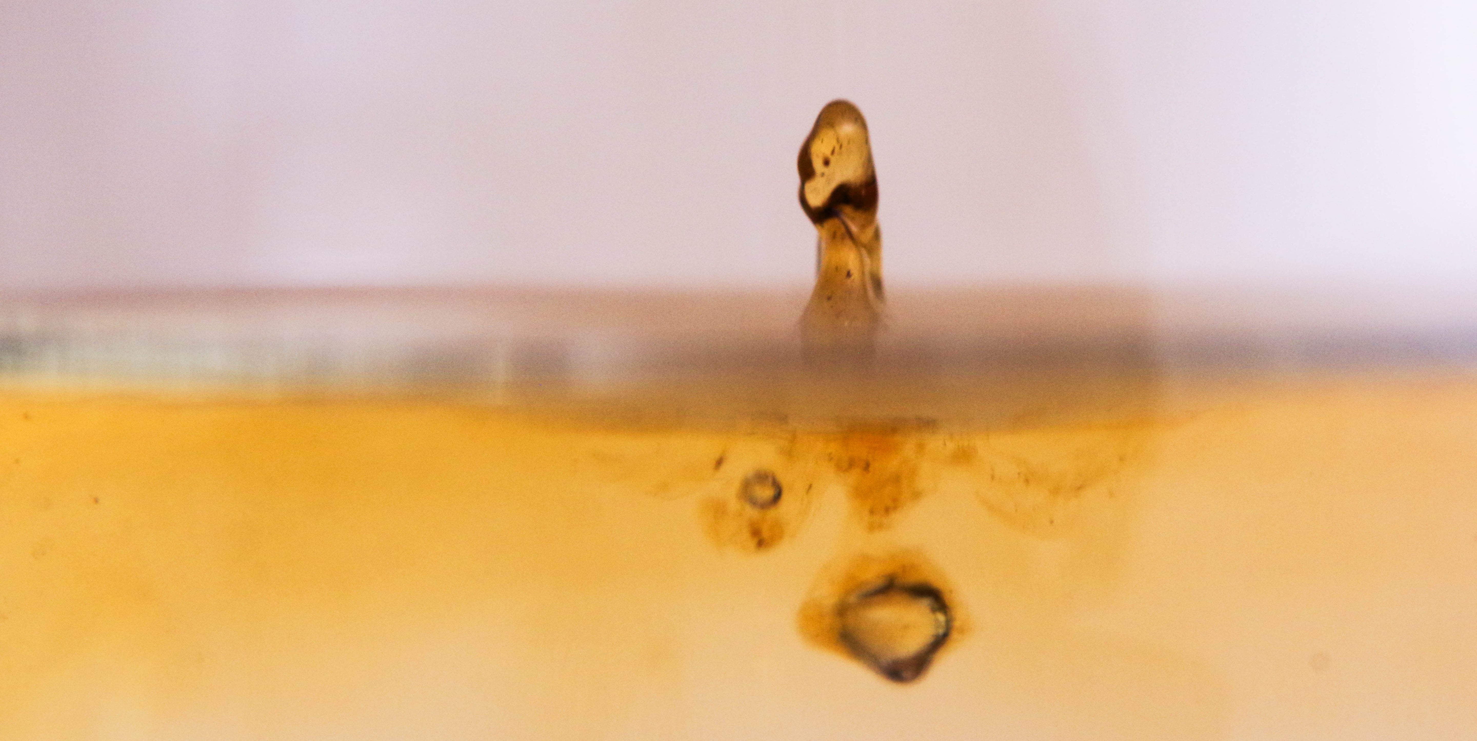 Gros plan sur une goutte de concentré liquide qui frappe une surface d'eau